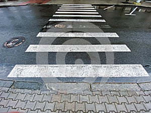 Pedestrian crosswalk with road marking on the wet asphalt road
