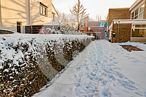 Pedestrian path in direction of a building with thick layer of snow with footprints