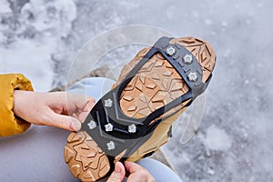 Pedestrian putting cleats on his shoes for extra traction during a winter walk during icy conditions.