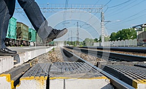 Pedestrian`s feet step on a pedestrian crossing through the rails at the railway station