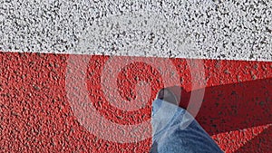 A pedestrian\'s legs cross a zebra crossing. Close-up of human legs