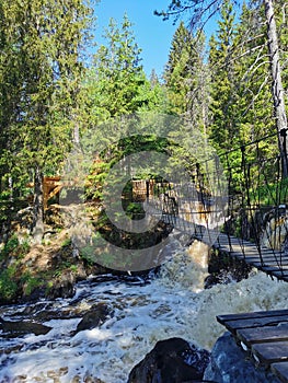 Pedestrian suspension bridge over the Ahvenkoski waterfall on the Tokhmayoki River in Karelia on a clear summer morning