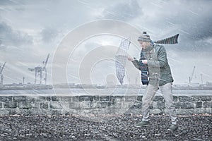 Pedestrian with an umbrella is facing strong wind and rain