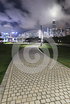 Pedestrian walkway in park and skyline of Hong Kong city at night
