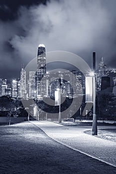 pedestrian walkway in park and skyline of Hong Kong city at night