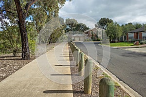 Pedestrian walkway in a quiet residential neighbourhood with some suburban houses in the distance.