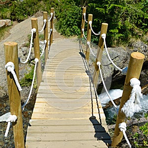 Pedestrian wooden bridge over mountain river photo