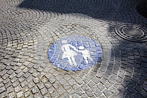 Pedestrian zone traffic sign in Germany, depicted by the silhouette of an adult holding the hand of a child, in white on a blue