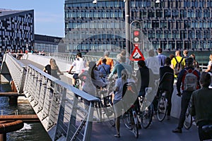 Pedestrians and people with bycycles waiting for a footbridge  to close before they can cross the water.