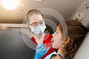 Pediatric dentist examines child girl mouth and teeth and treats toothaches. Happy child patient of dentistry