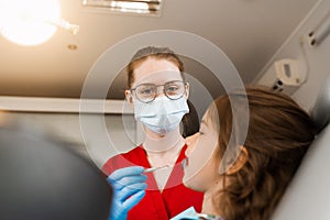 Pediatric dentist examines child girl mouth and teeth and treats toothaches. Happy child patient of dentistry