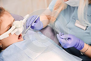 Pediatric dentist examining child teeth with dental explorer and mirror.