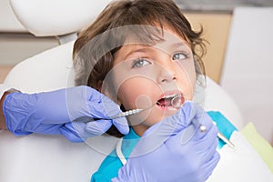 Pediatric dentist examining a little boys teeth in the dentists chair