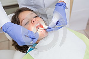 Pediatric dentist examining a little boys teeth in the dentists chair