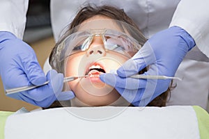 Pediatric dentist examining a little boys teeth in the dentists chair photo