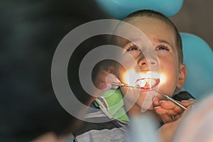 Pediatric dentist examining a little boys teeth in the dentists chair at the dental clinic. A child with a dentist in a dental