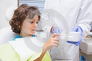 Pediatric dentist showing little boy teeth model