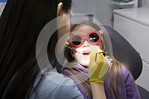 pediatric dentistry close-up little girl opened mouth shows teeth doctor looks at whether she has caries fillings