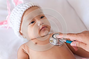 Pediatric doctor exams newborn baby girl with stethoscope in hos