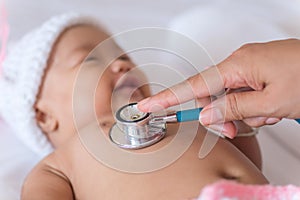 Pediatric doctor exams newborn baby girl with stethoscope in hos