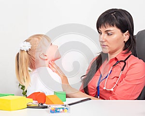 A pediatric otolaryngologist doctor probes the tonsils on the throat of a little girl 3 years old. The concept of sore throat in