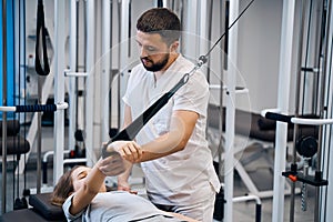 Pediatric physiotherapist working with little girl in rehabilitation center on elastic simulators