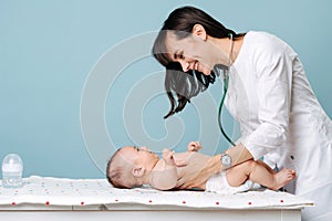 Pediatrician brunette in a white robe examines the baby