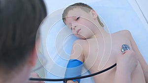Pediatrician cardiologist listening heartbeat of child boy using stethoscope.