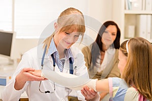 Pediatrician checking bandage girl arm