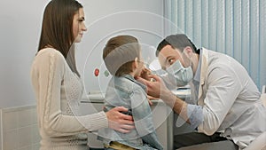 Pediatrician checking little boy throat
