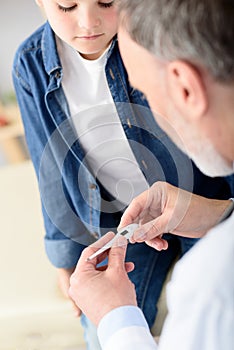 Pediatrician checking temperature of sick patient