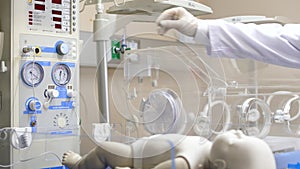 A pediatrician ckecking settings on an infant radiator/resuscitator unit.