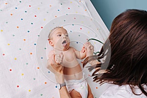 Pediatrician doctor checks the baby`s grasping reflexes photo