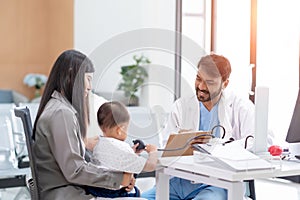 Pediatrician doctor consulting Asian mother about her little son health. Mother and son talking to therapist at consultation in