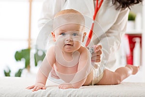 Pediatrician doctor examines baby boy with stethoscope checking heart beat