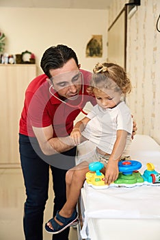 Pediatrician doctor examining child. Male doctor examining boy's ear with otoscope in hospital.