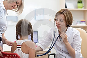 Pediatrician doctor examining kid patient with stethoscope
