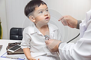 Pediatrician doctor examining a little asian boy by stethoscope