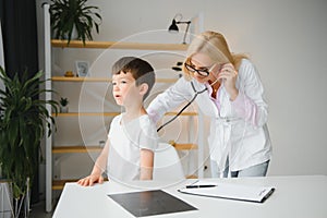 Pediatrician doctor examining little boy& x27;s heart beat and lungs to check for problems