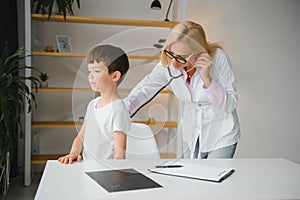 Pediatrician doctor examining little boy's heart beat and lungs to check for problems