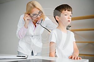 Pediatrician doctor examining little boy& x27;s heart beat and lungs to check for problems