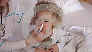 Pediatrician doctor using nasal spray for stuffy nose cute girl patient