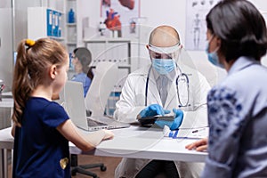 Pediatrician doctor writing notes on notepad during medical checkup examination