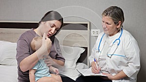Pediatrician does checkup of baby sitting on mother lap