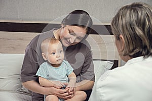 Pediatrician does checkup of baby sitting on mother lap
