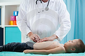 Pediatrician doing abdominal examination photo