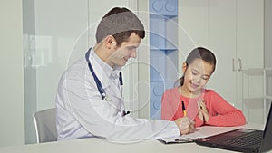 Pediatrician draws on clipboard near the little girl