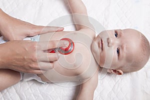 Pediatrician examines three months baby boy using a stethoscope