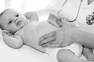 Pediatrician examining baby, black and white