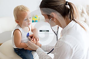 Pediatrician examining baby boy. Doctor using stethoscope to listen to kid